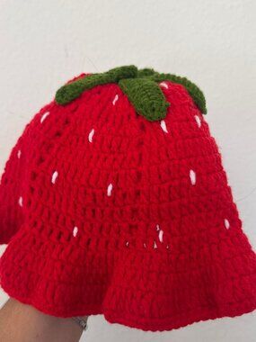 Red crochet strawberry hat with white seed details and green leaf top